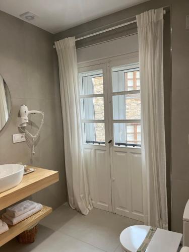 a bathroom with a sink and a door with a window at Cantábrico Fonsagrada in Fonsagrada