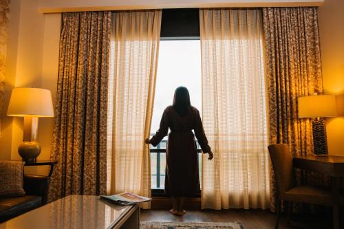 a woman standing in a hotel room looking out the window at The Brownwood Hotel & Spa in The Villages
