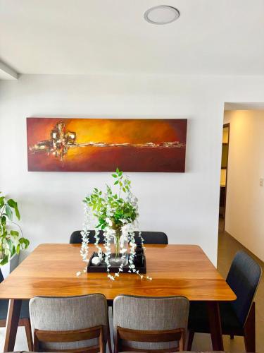 a dining room table with chairs and a painting on the wall at New Bamboo Horizon pool, gym and coworking in Querétaro