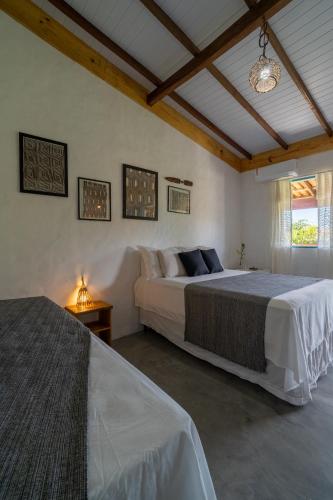 a bedroom with two beds and a chandelier at Pousada Kiarô Caraíva in Caraíva