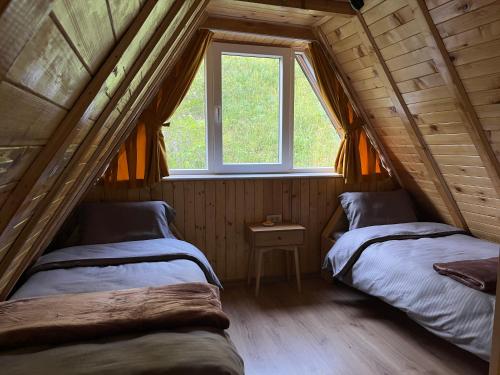 two beds in a room with a window at Evergreen Tiny Homes in Peje