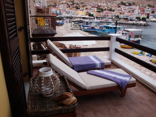 a balcony with chairs and a view of a harbor at Halkis Muses in Halki