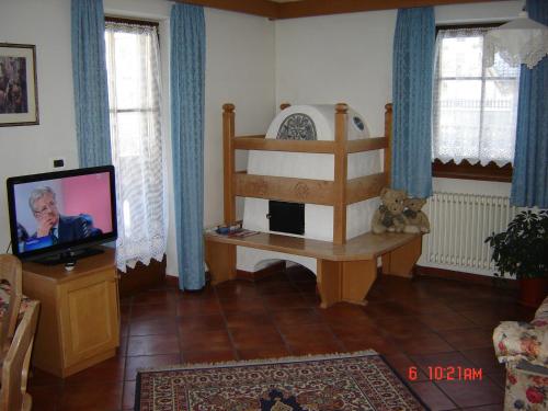 a living room with a tv and a crib at Hotel Stella Alpina in Moena