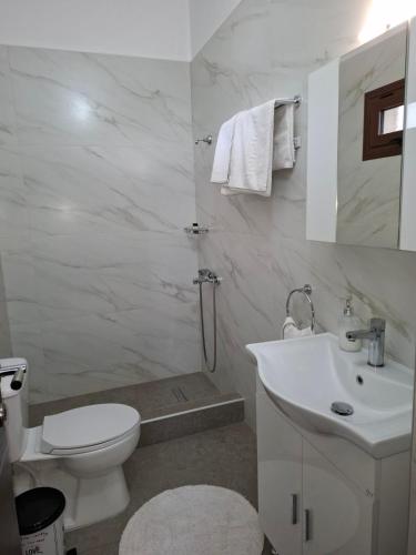 a white bathroom with a toilet and a sink at Guesthouse Athanasiou in Kato Loutraki