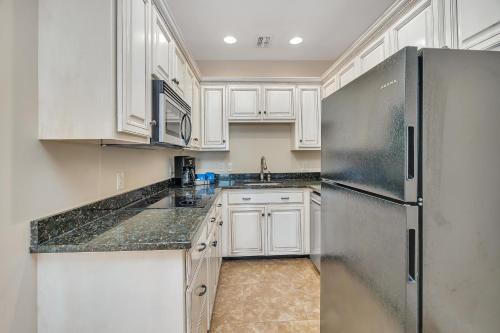 a kitchen with white cabinets and a stainless steel refrigerator at Sea Gate #102 in Saint Simons Island