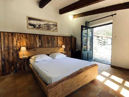 ein Schlafzimmer mit einem Bett mit einer Holzwand in der Unterkunft Maison des Cévennes in Arphy