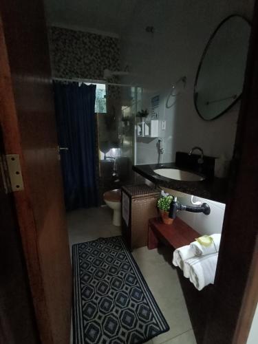 a bathroom with a sink and a toilet and a mirror at Casa LuPi in Carmo do Rio Claro