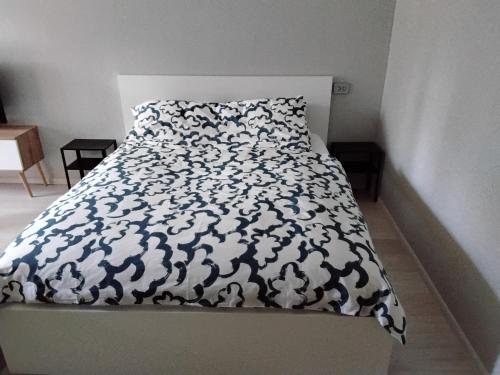 a bed with a black and white comforter and pillow at Svečių butas in Šiauliai
