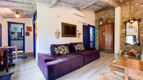 a living room with a purple couch and a table at Segredo da Serra Guest House in Tiradentes
