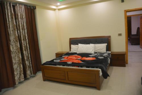 a bedroom with a bed with black sheets and orange flowers on it at Hotel Rock Star, Naran in Nārān