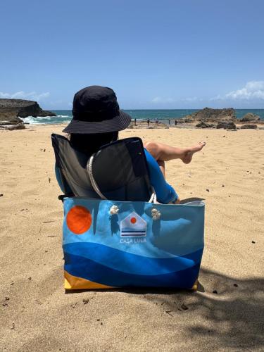 a person sitting in a chair on the beach at Casa Lula Beach Retreat - Fenced backyard in Arecibo