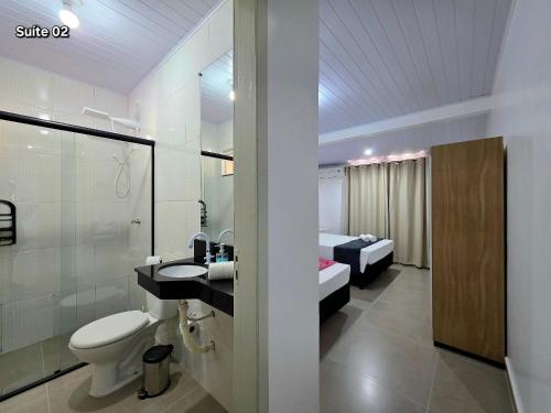 a bathroom with a toilet and a sink and a bed at Casa 2 Suítes + 2 quartos piscina e churrasqueira in Foz do Iguaçu