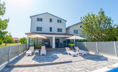 a patio with chairs and umbrellas in front of a building at Villa Dar Počitelj in Čapljina