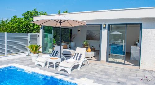 a patio with chairs and an umbrella next to a pool at Villa Dar Počitelj in Čapljina