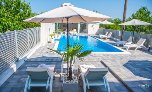 a swimming pool with an umbrella and chairs and a table at Villa Dar Počitelj in Čapljina