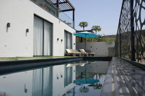 Cidade VelhaCORAL BAY - Kode Villa的一座带遮阳伞的游泳池的房子