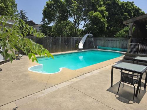 une piscine dans une cour arrière avec une table et un toboggan aquatique dans l'établissement Luxury home 4BR, Pool, & 5 Mins to 401, à Whitby