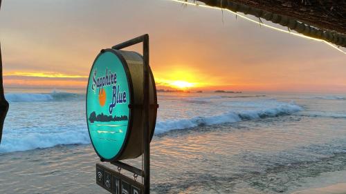 una tabla de surf en la playa con la puesta de sol en el fondo en Sapphire Blue, en Hikkaduwa