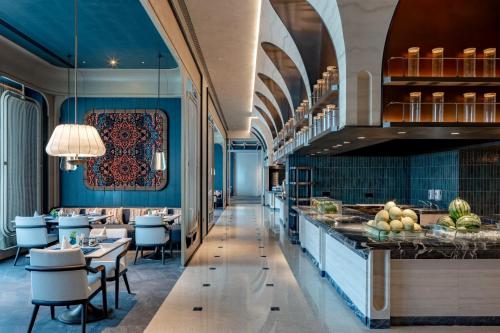ein Restaurant mit blauen Wänden, Tischen und Stühlen in der Unterkunft InterContinental Hotels Yining by IHG in Yining