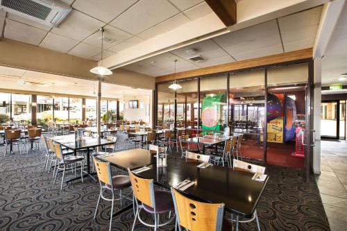 a dining room with tables and chairs and windows at Nightcap at Riverside Hotel in Launceston