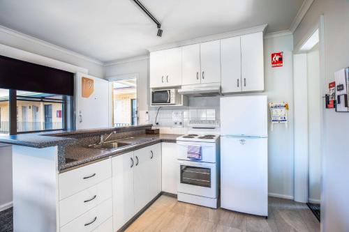 a white kitchen with white cabinets and appliances at Nightcap at Riverside Hotel in Launceston