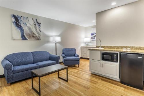 a living room with two blue chairs and a kitchen at Best Western Mystic Hotel in Mystic