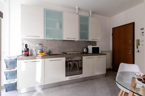 a kitchen with white cabinets and a stove top oven at Patio & Parking - Self check-in & Remote access in Cernobbio
