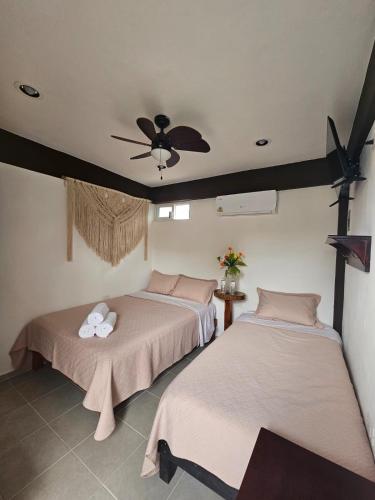 two beds in a room with a ceiling fan at Hotel Pueblo Viejo in Valladolid