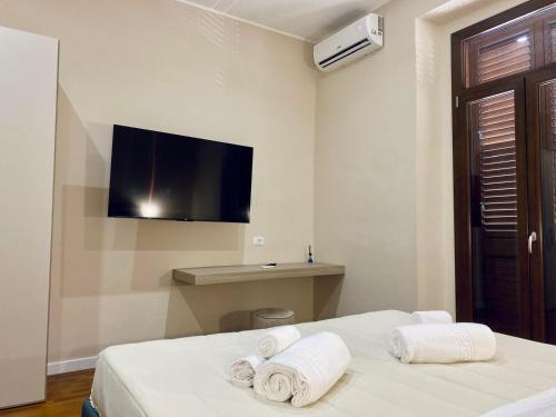 a hotel room with a bed with towels and a flat screen tv at Helios Home in Reggio Calabria