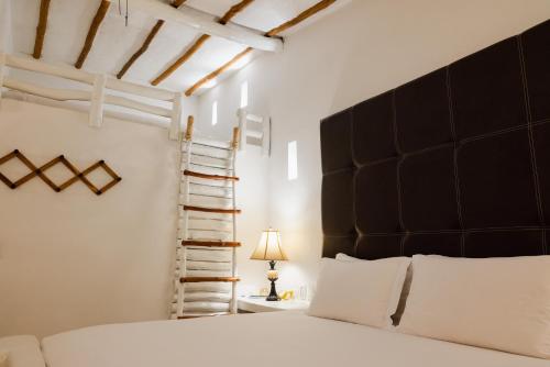 a bedroom with a bed with a black headboard and a ladder at Posada & Spa La Ardileña en Morrocoy in La Luisa