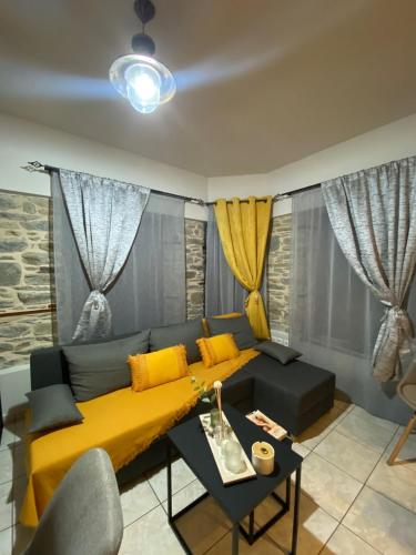a living room with a yellow couch and a table at Little square house in Argalasti