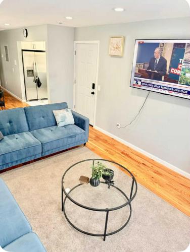 a living room with a blue couch and a tv at Luxurious, Spacious, Modern 6 BR Escape with parkings and sleeps up to 16 in Irvington