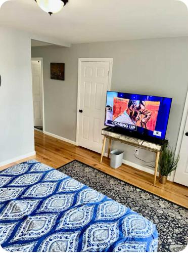 a bedroom with a bed and a flat screen tv at Luxurious, Spacious, Modern 6 BR Escape with parkings and sleeps up to 16 in Irvington