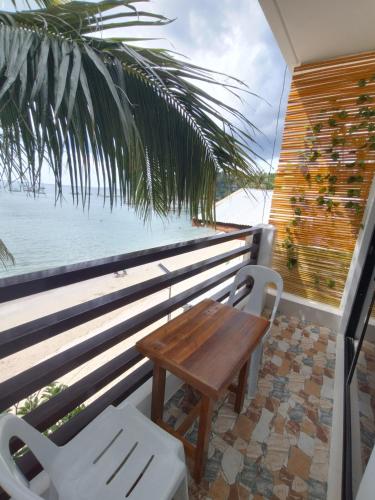 a wooden table and chairs on a balcony with the ocean at Joyful Guest House in El Nido