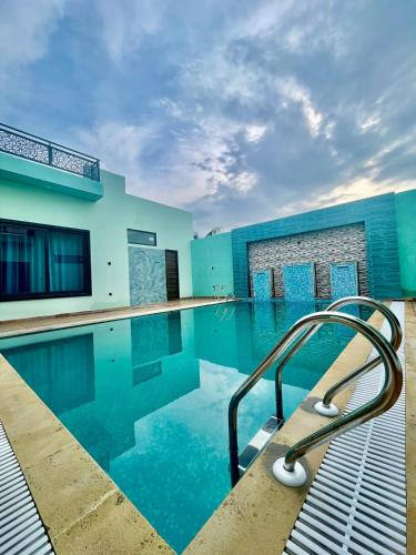 a swimming pool with a metal handrail in the water at ZenRoofs - Pool Farm House in Jaipur