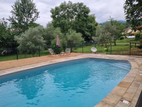 a pool in a yard with two chairs and a umbrella at Hôtel La Cachette de Nina- Madame rêve - Saint-Girons in Saint-Girons