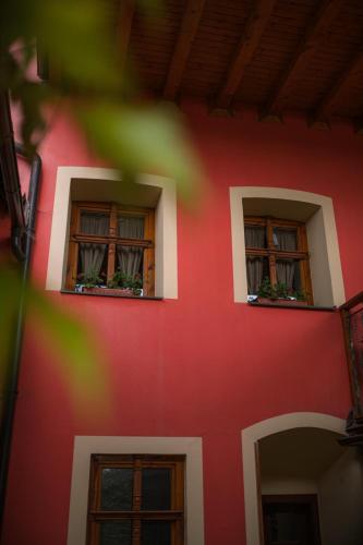 two windows on a red building with plants in them at Vila Zipser in Poprad
