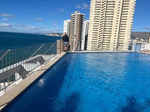 a man standing on the balcony of a building with a swimming pool at Observador de delfines in Benidorm