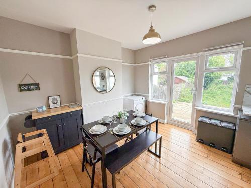 a dining room with a table and a kitchen at Spacious 3BDR House in New Malden with FREE Parking and Garden near Kingston upon Thames, Wimbledon & Raynes Park by Staylio London in Worcester Park