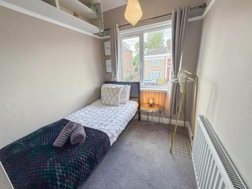 a small bedroom with a bed and a window at Spacious 3BDR House in New Malden with FREE Parking and Garden near Kingston upon Thames, Wimbledon & Raynes Park by Staylio London in Worcester Park