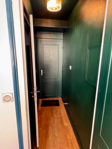 a hallway with a green wall and a door at Le Studio du Coq - Proche du Zoo de Beauval et des châteaux in Selles-sur-Cher