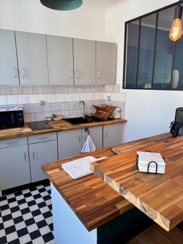 a kitchen with white cabinets and a wooden counter top at Le Studio du Coq - Proche du Zoo de Beauval et des châteaux in Selles-sur-Cher