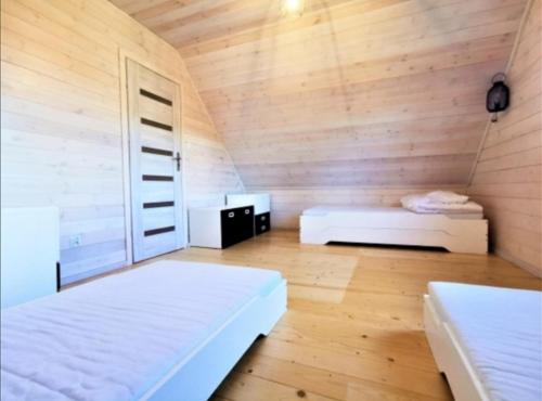 a bedroom with two beds and a wooden wall at Biały domek nad jeziorem in Stegers