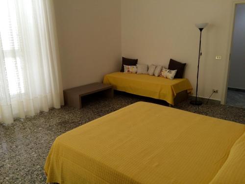 two beds in a room with yellow sheets at B&B Zia Iaia in Siderno Marina