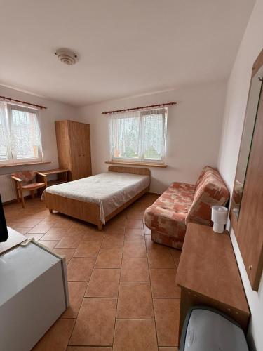 a bedroom with a bed and a couch at Dom Wczasowy Mateusz in Rewal