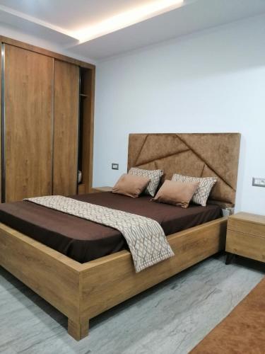 a bedroom with a large bed with a wooden headboard at Les Flots D'ezzahra in Ḩammām al Ghazzāz