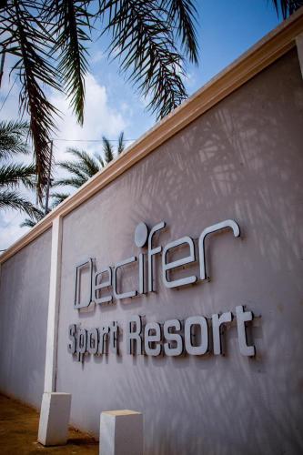 a sign for a resort with a palm tree at Decifer Sport Resort in Belas