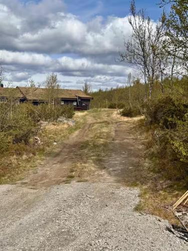 a dirt road with a house in the distance at Geilo - Charming cottage with a stunning view in Geilo