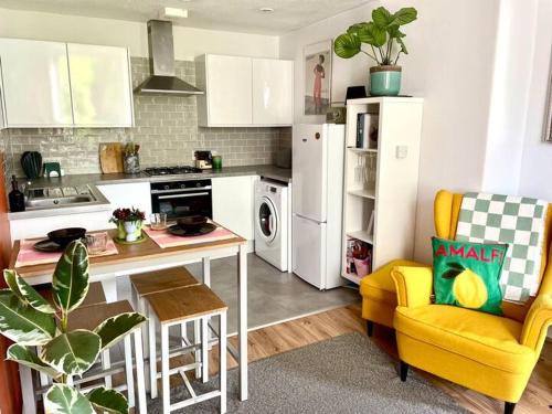 a kitchen with a table and a yellow chair at Quiet 1 Bed with Garden Views Near Leith & City Centre in Edinburgh