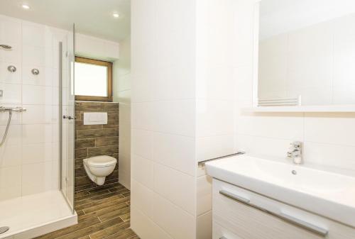 a white bathroom with a toilet and a sink at Gschwenderhaus Ferienwohnungen in Oberstdorf
